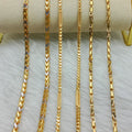 Gold chains of different lengths displayed on a white surface