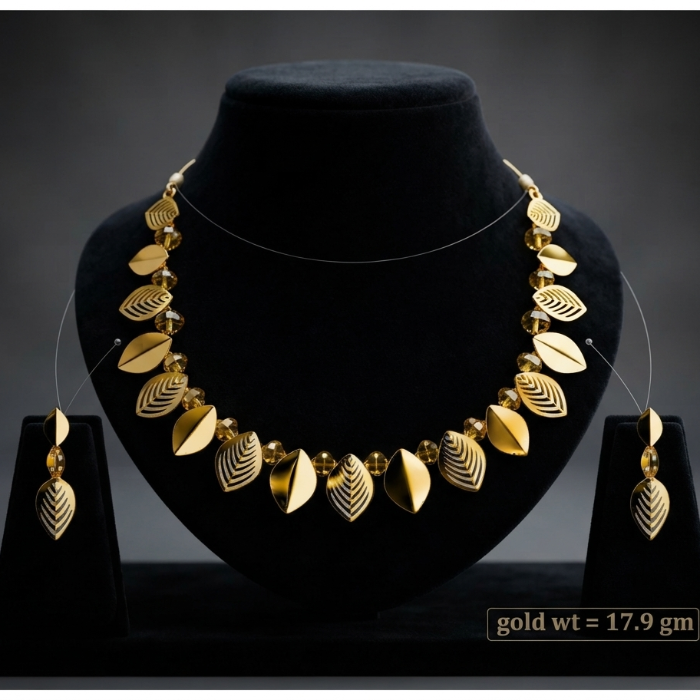 Gold-toned jewelry set displayed on a black velvet bust, including a necklace with leaf-shaped elements and matching drop earrings, shown against a dark gray studio background. A small text box at the bottom right reads 'gold wt = 17.