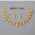 Gold jewelry set featuring a necklace and matching earrings with textured, wave-like leaf or ribbon motifs and small floral accents, displayed on a plain gray background with text reading 'gold wt = 15 gm'.