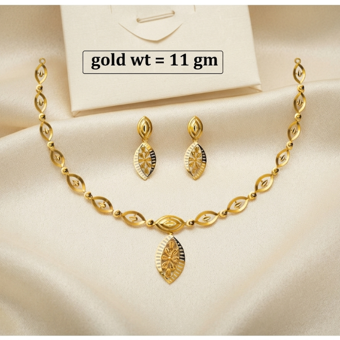 Gold jewelry set featuring a necklace and matching earrings with a textured sunburst design, displayed on a cream satin fabric background with a white box and a text overlay indicating 'gold wt = 11 gm'.