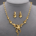 Gold floral necklace and matching stud earrings displayed on a gray jewelry bust against a dark gray background.