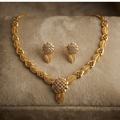 Gold leaf-patterned necklace and matching earrings displayed on a beige velvet jewelry box.