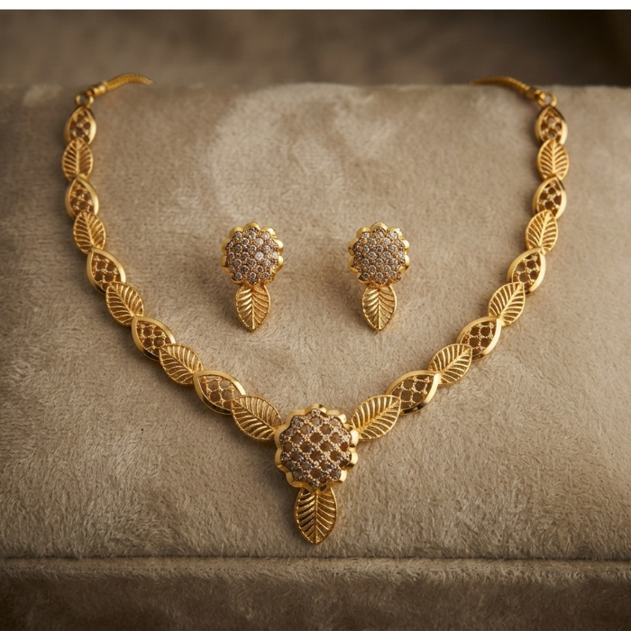 Gold leaf-patterned necklace and matching earrings displayed on a beige velvet jewelry box.