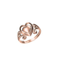A rose gold ring featuring a central heart motif with an openwork scroll design on the band, shown against a plain white background with a small product code label and logo at the bottom.
