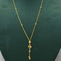 A gold necklace with a delicate chain, small bead accents, and a dangling heart-shaped pendant, displayed on a dark green jewelry bust.
