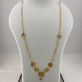 A gold necklace displayed on a white mannequin bust, with a digital scale visible underneath. The necklace features a delicate chain with ornate circular floral motifs and a central pendant.