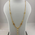 A gold necklace displayed on a white jewelry bust, with a digital scale visible underneath. The necklace features a textured chain with small circular and oval links and a dangling pendant.
