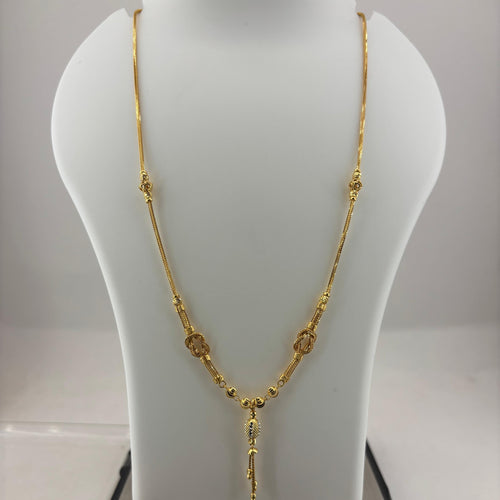 A gold necklace displayed on a white jewelry bust, with a digital scale visible underneath. The necklace features a textured chain with small circular and oval links and a dangling pendant.