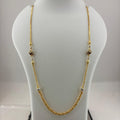 A gold chain necklace with small decorative beads displayed on a white jewelry bust, with a digital scale visible underneath.