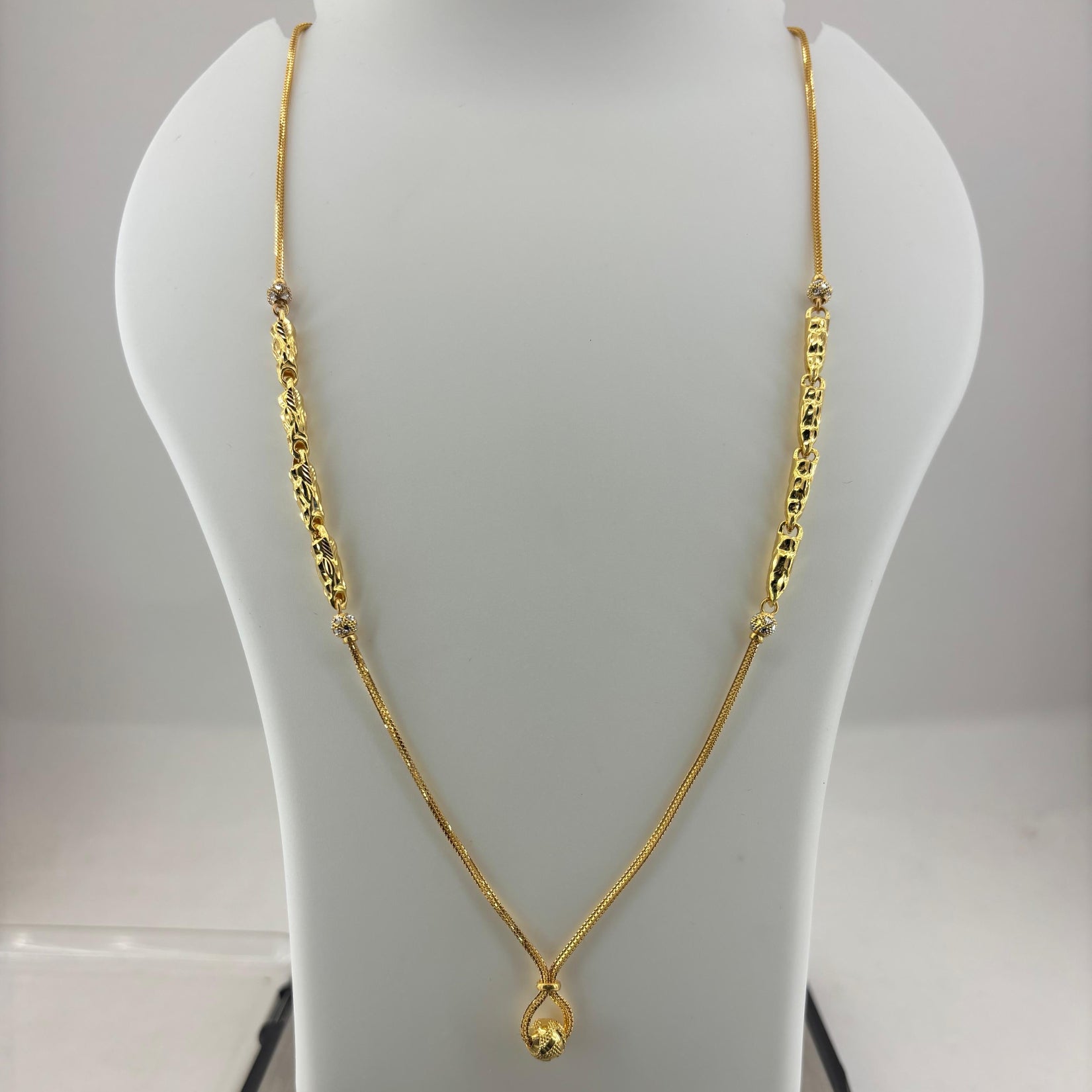A gold necklace with a teardrop pendant displayed on a white mannequin bust, with a digital scale underneath showing a weight of 8.14 grams.