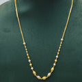 A gold chain necklace with small white bead accents displayed on a dark green jewelry bust.