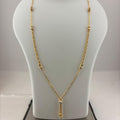 A gold necklace displayed on a white jewelry bust, with a digital scale visible underneath. The necklace has a delicate chain with small bead details and a central pendant with a clear stone.