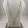A gold necklace displayed on a white jewelry bust, with a digital scale underneath to show weight. The necklace features a textured chain and a pendant with a small central heart-shaped detail.