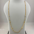 A gold necklace with small silver and gold beads and a heart-shaped clasp, displayed on a white jewelry bust sitting on a digital scale.
