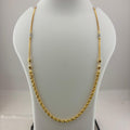 A gold chain necklace displayed on a white mannequin bust, with a digital scale visible underneath. The necklace has a twisted rope style with small bead accents.
