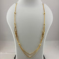 A gold-toned multi-strand necklace with textured bead details, displayed on a white jewelry bust stand with a digital scale underneath.