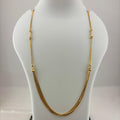 A gold chain necklace displayed on a white mannequin bust, with a digital scale visible underneath.