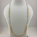 A gold chain necklace displayed on a white mannequin bust, with a digital scale visible underneath. The necklace features a smooth curved section at the bottom and small bead details spaced along the chain.
