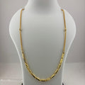A gold chain necklace displayed on a white jewelry bust, with a digital scale visible underneath.