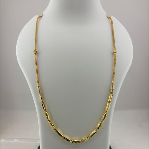 A gold chain necklace displayed on a white jewelry bust, with a digital scale visible underneath.