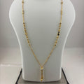 A gold necklace displayed on a white mannequin bust, with a digital scale visible underneath to show the weight. The necklace features a delicate chain with small bead details and a central pendant.