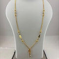 A gold necklace with small metallic beads and a key-shaped pendant, displayed on a white jewelry bust that sits on a digital scale.