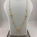A gold-toned multi-strand necklace with a small pendant, displayed on a white mannequin bust sitting on a digital scale showing 8.54 grams.