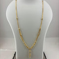 A gold necklace displayed on a white jewelry bust, with a digital scale visible underneath. The necklace features a delicate chain with small bead details and a central pendant with a clear stone.
