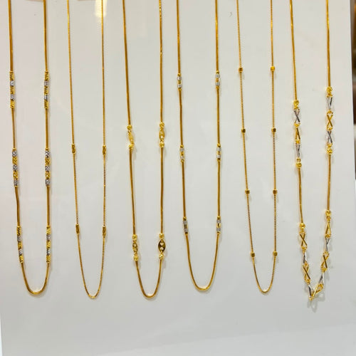 Nine gold chains of varying lengths and styles displayed on a white stand, each with a small price tag attached.
