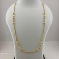 A gold chain necklace with small bead accents displayed on a white mannequin bust, with a digital scale visible underneath.