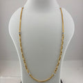 A gold chain necklace displayed on a white mannequin bust, with a digital scale visible underneath. The necklace has small silver-toned bead accents spaced along the chain.