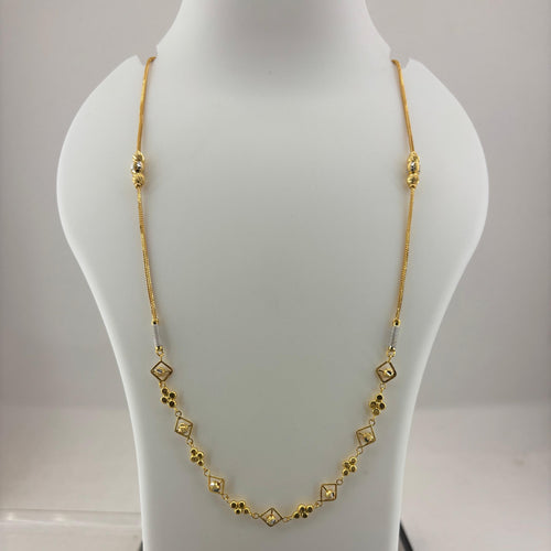 A gold chain necklace with small diamond-shaped and floral motifs displayed on a white mannequin bust, with a digital scale visible underneath.