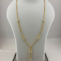 A gold necklace displayed on a white jewelry bust, with a digital scale visible underneath. The necklace has a Y-shaped design with small bead details along the chain.