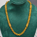 A gold-toned chain necklace displayed on a dark green velvet jewelry bust