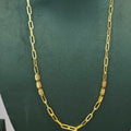 A gold chain necklace with alternating flat oval links and textured cylindrical links, displayed on a dark green velvet jewelry bust.