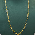 A gold chain necklace with elongated oval links, displayed on a dark green velvet jewelry bust.