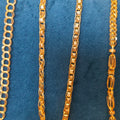 Gold chain necklace displayed on a blue velvet jewelry bust, showing multiple chain styles including curb, box, and Spanish link.