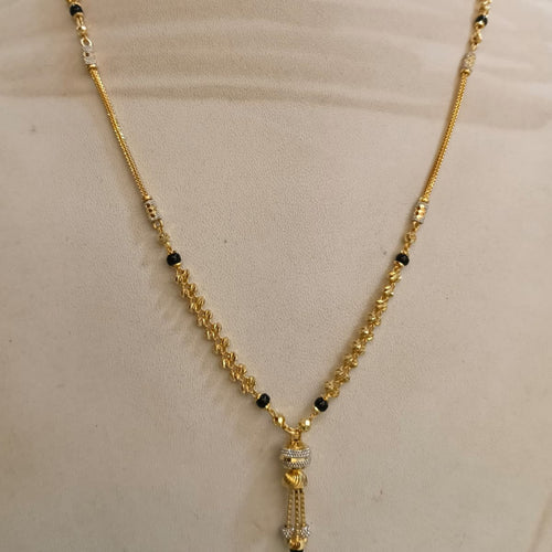 Gold chain necklace with small black bead accents and a dangling tassel pendant, displayed on a beige mannequin bust.