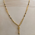 A gold necklace with small black bead accents displayed on a cream-colored mannequin bust.