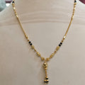 Gold necklace with small black bead accents and a dangling pendant, displayed on a beige mannequin bust.