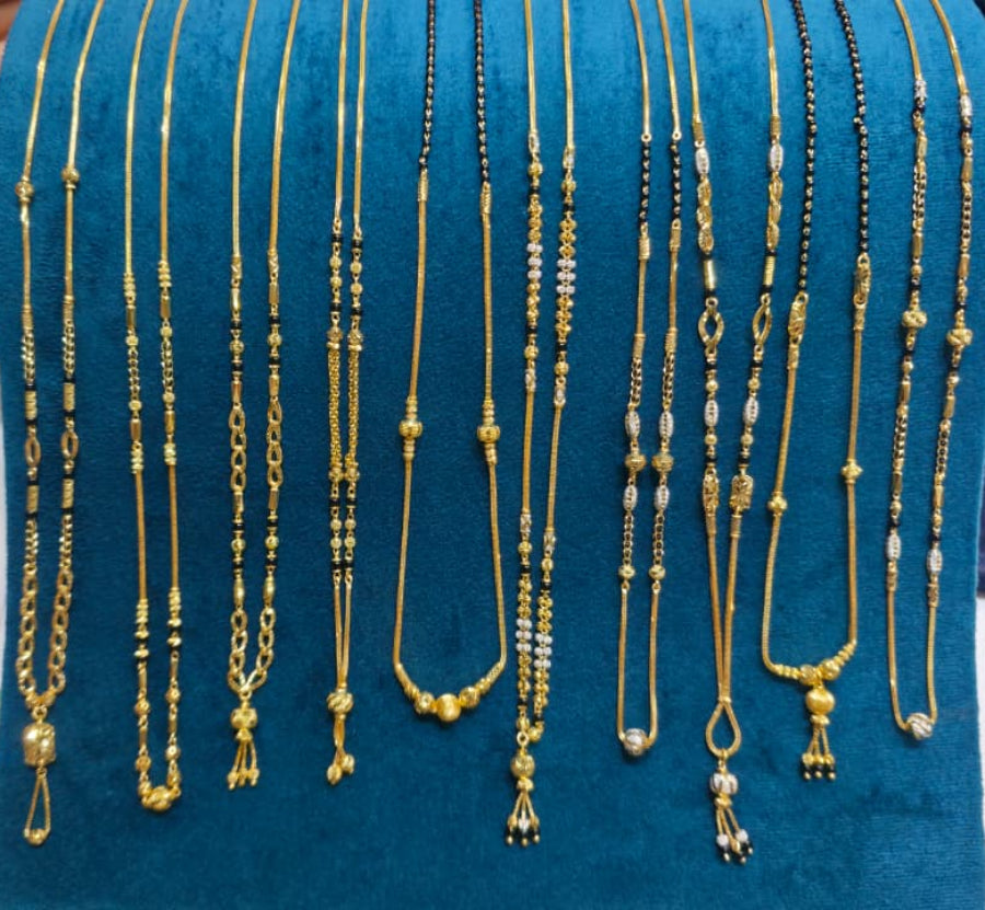 A hand holds up a teal velvet jewelry display bust filled with multiple gold-tone and black beaded necklaces, shown against a retail counter with papers and a phone in the background.