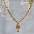 Gold necklace with a pendant on a clear plastic background