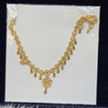 Gold necklace on a clear plastic sheet with a black background