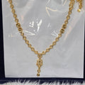Gold necklace on a white card with a clear plastic cover