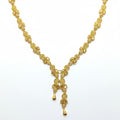 Gold necklace on a white card with a hand touching the top left corner.